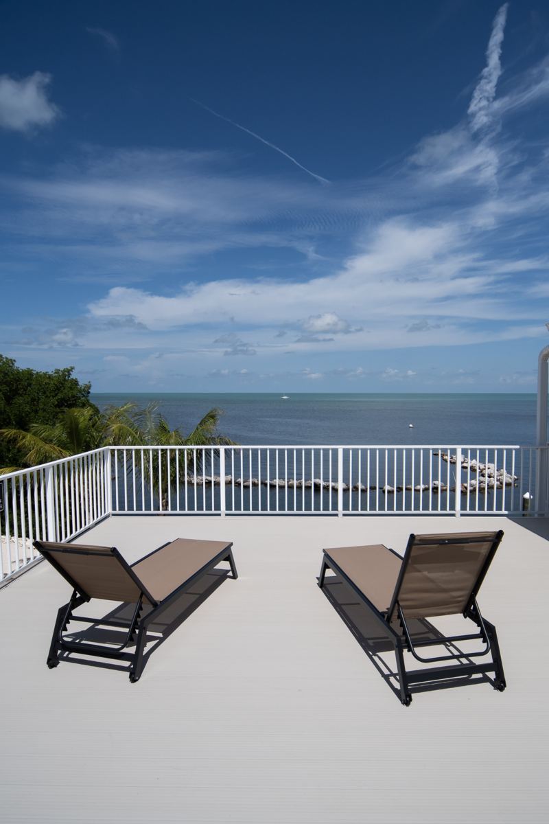 Two lounge chairs on the open sun deck above the water