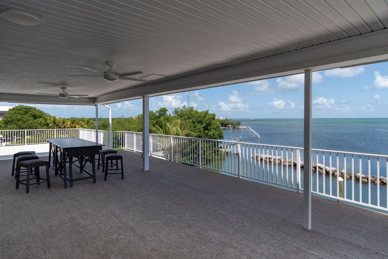 Covered deck with dining tables, ceiling fans and water views