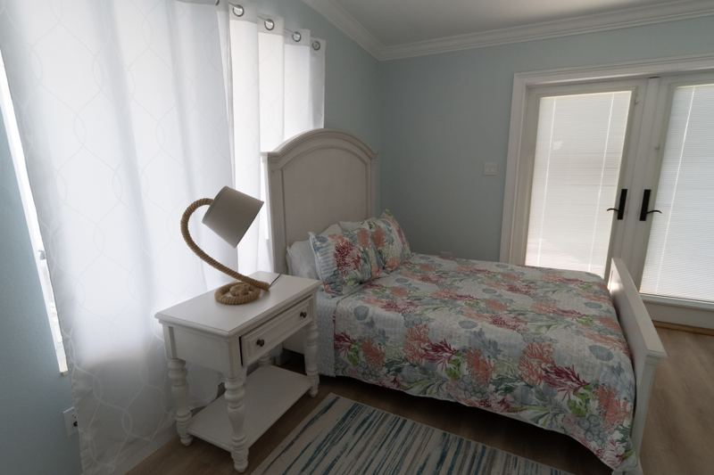 Full bed and nightstand beside French doors