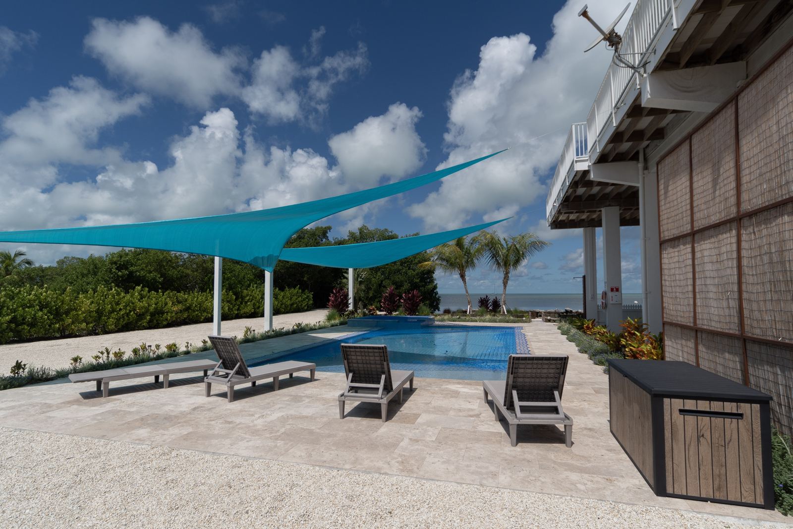 Climate-controlled pool with shade sails and lounge chairs